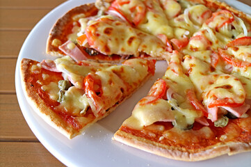 Delectable Crispy Cheesy Ham and Tomato Pizza on a White Plate