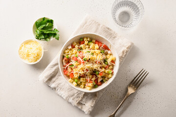 Italian salad with ditalini pasta, tomatoes, sausage on white table. View from above.