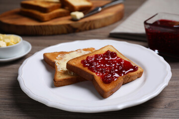 Fresh toast with jam and butter served on wooden table, closeup