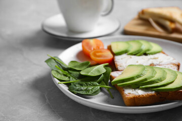 Sandwiches with avocado and spinach served on grey  table, closeup