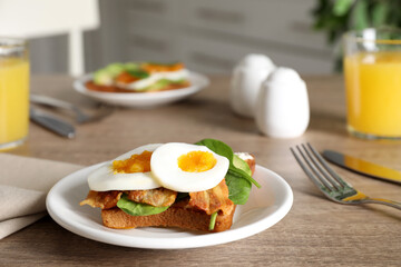 Sandwich with egg, bacon and spinach served on wooden table