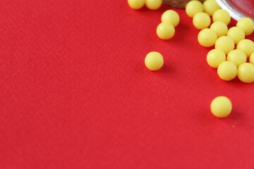 Homeopathy vitamins are scattered on a red background with a copyspace place for text.