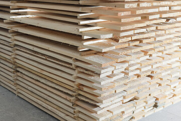 Wooden boards are stacked in a sawmill or carpentry shop. Sawing drying and marketing of wood. Industrial background