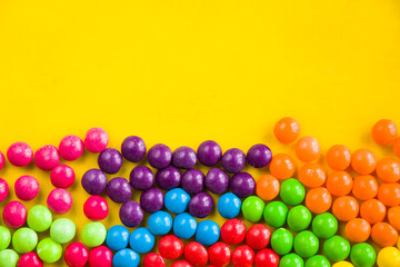 Skittles candy on the yellow table, colorful sweet candy background