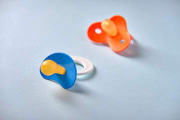Multicolored baby pacifiers on a blue background