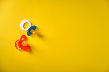 Baby pacifiers on a yellow background, place for an inscription