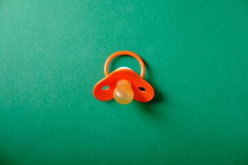 Baby pacifier on a green background, place for an inscription
