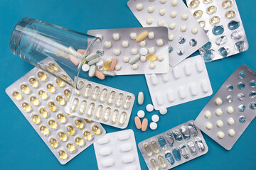 whole and open pills, vitamins and an inverted glass lie on the table