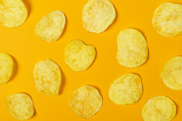 Slices of natural potato chips on cheerful orange background.