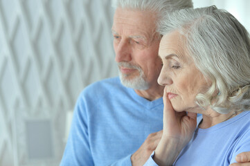 Portrait of sad senior couple posing at home