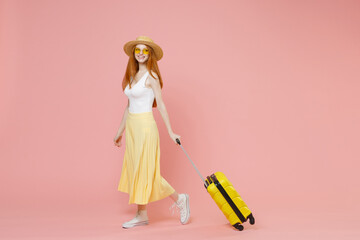 Full length body traveler tourist woman in summer clothes straw hat glasses going with suitcase valise isolated on pink background Passenger travel abroad weekends getaway Air flight journey concept.