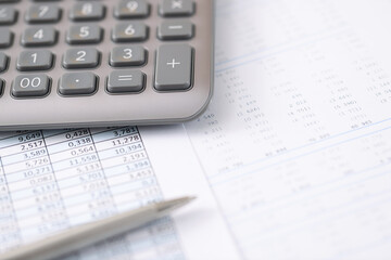 On table is a calculator pen and document with financial report