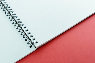 Open notebook with spring on red background for writing. Copy space.