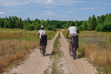Mom and Dad ride children on bicycles on a blooming field