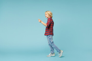 Full length side view of funny little curly kid boy 10s in basic red checkered shirt pointing index...