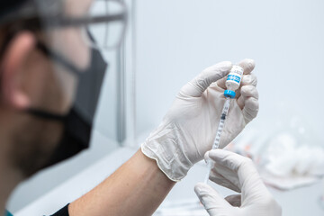 CU COVID-19 vaccine in doctor hands, male doctor holds syringe and bottle with vaccine for coronavirus cure. Concept of corona virus treatment, injection, vaccination, clinical trial during pandemic