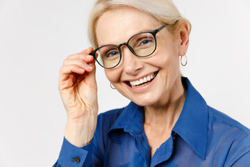 Close up blonde smiling happy confident employee business woman 40s wearing blue classic shirt glasses formal clothes looking camera touching glasses isolated on white background studio portrait.