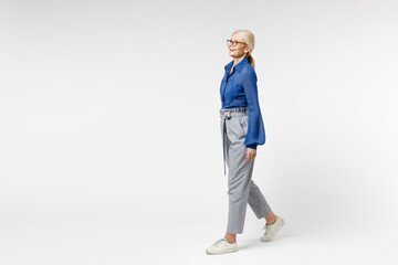 Full length side view blonde pensive happy successful employee business woman 40s in blue classic shirt gray pants glasses formal clothes walking going isolated on white background studio portrait.