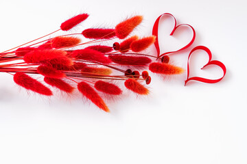 A bouquet of dry bright red herbs on a white background. Heart-shaped red ribbons. Happy Valentine's Day and other holidays greetings with copy space