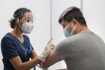 African American Black female Doctor prepares to administer vaccine to a Chinese patient in...