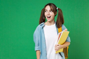 Excited young woman student in basic blue shirt backpack hold notebooks keeping mouth open looking...