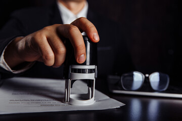 Close-up of businessman hand using stamper on document.