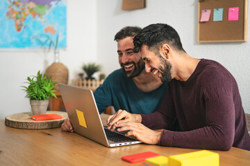 Gay men couple using laptop in living room at home - Homosexual love and gender equality in relationship concept - Powered by Adobe