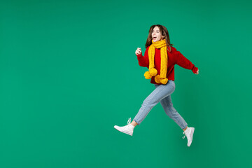 Fototapeta na wymiar Full length side view of cheerful funny young brunette woman 20s wearing basic casual knitted red sweater yellow scarf jumping like running isolated on bright green color background studio portrait.