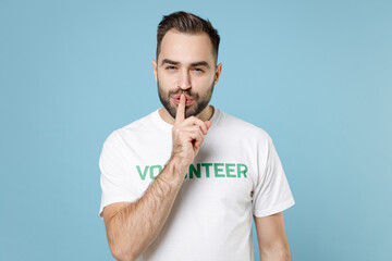 Secret young man in white volunteer t-shirt say hush be quiet with finger on lips shhh gesture...