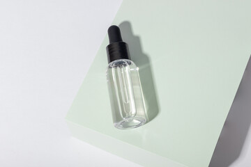 Glass cosmetic bottle with dropper on stand. Transparent container for cream, lotion, serum and face mask. The concept of environmentally friendly, organic cosmetology.