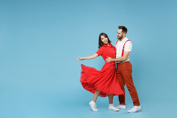 Full length of funny young couple two friends man woman in white red clothes hugging dancing having fun isolated on pastel blue color background studio portrait. St. Valentine's Day holiday concept. - obrazy, fototapety, plakaty