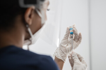 CU COVID-19 vaccine in doctor hands, African American Black female doctor holds syringe and bottle...