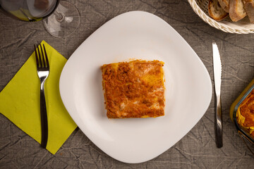 Lasagna Bolognese on the white plate. The famous and classic first course of Italian cuisine. Flat lay.
