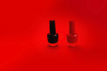 Red and black nail polish isolated on red background. Beauty, fashion, care concept.