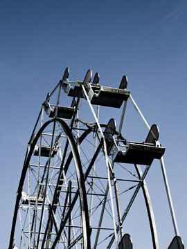 The top of an empty ferris wheel stands cold against a dark blue sky.