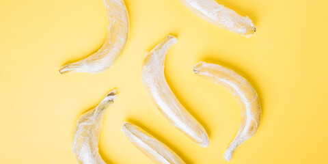Banana fruits wrapped in stretch wrap on yellow background