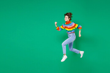 Full length side view of smiling cheerful pretty young brunette woman 20s years old in basic casual colorful sweater jumping like running isolated on bright green color background studio portrait.