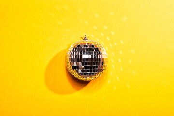 Mirror gray disco ball on yellow illuminating paper background. Party ultimate concept. Flat lay...