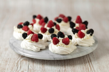 Pavlova cake. The cakes are on a marble platter. Sweet Dessert. A treat for guests. Dessert for the holiday. Cake decorated with berries.