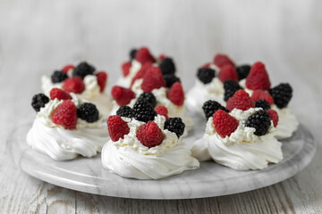 Pavlova cake. The cakes are on a marble platter. Sweet Dessert. A treat for guests. Dessert for the holiday. Cake decorated with berries.