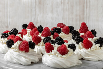 Pavlova cake. The cakes are on a marble platter. Sweet Dessert. A treat for guests. Dessert for the holiday. Cake decorated with berries.