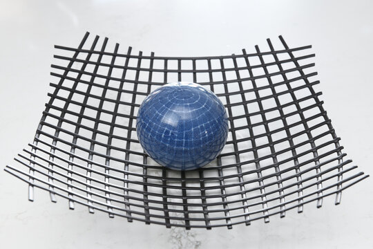 Blue orb sitting on wire mesh looking like earth distorting spacetime to produce gravity