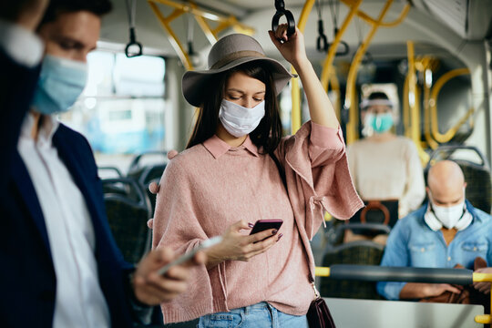 Woman With Protective Face Mask Texting On Mobile Phone While Commuting By Bus.