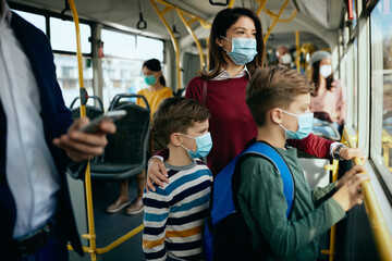 Fototapeta na wymiar Mother and kids wearing protective face masks while commuting by public transport.