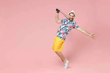 Full length side view of funny traveler tourist man in summer clothes hat hold photo camera stand on toes dancing isolated on pink background. Passenger travel on weekends. Air flight journey concept.