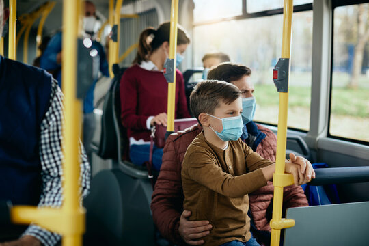 Small boy and father wearing protective face masks while commuting by bus.