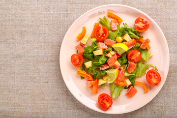 Salmon salad with cherry tomatoes and green salad in a plate of gray tablecloth. Copy space.