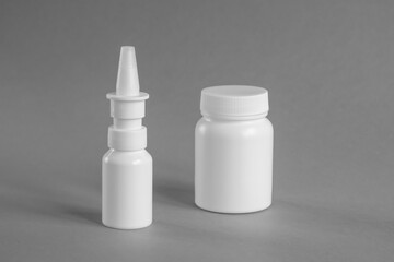 Blank Medicine bottle. White plastic medical containers for medicines and nasal spray (decongestant) on gray background, mockup. Pharmacy business and treatment concept. Copy space. Close-up.