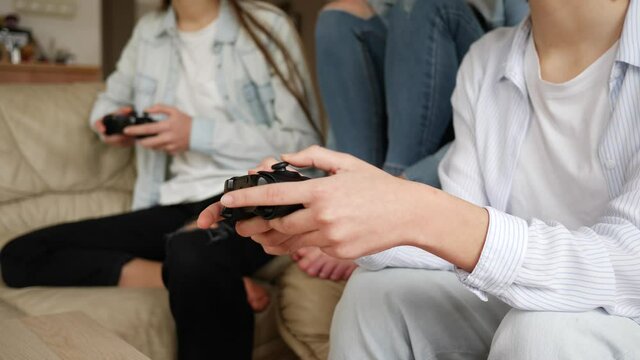 Teenager girls at home triplet sisters have fun play console games sitting on couch at home stay isolated under quarantine