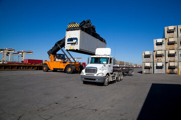 Mobile crane lifting up container in railroad yard